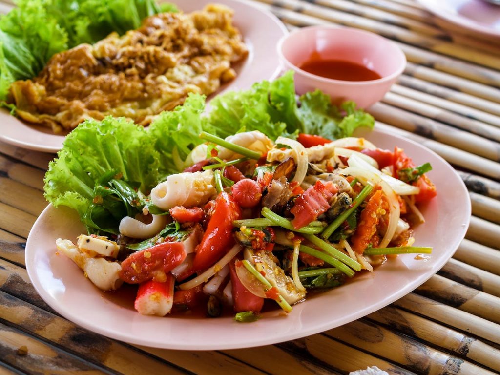 sliced-vegetable-and-cooked-food-on-white-ceramic-plate-1234535 Authentic Thai seafood salad with fresh vegetables and herbs served on a pink plate.